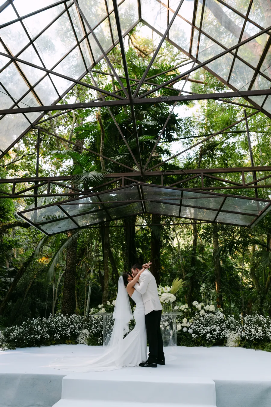 Casal se beijando no altar sob cúpula de flores