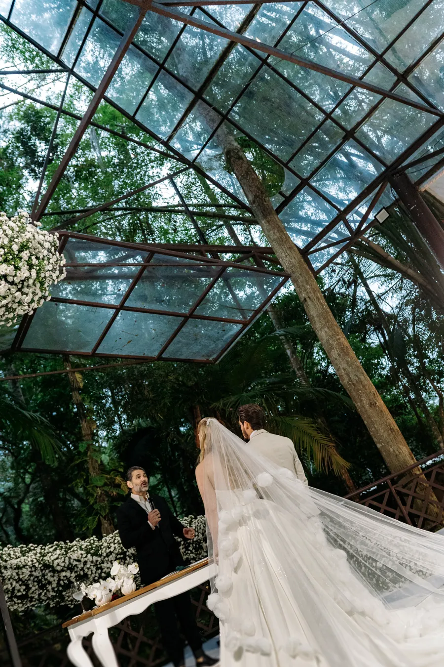 Casal sob o teto de vidro com véu ao vento